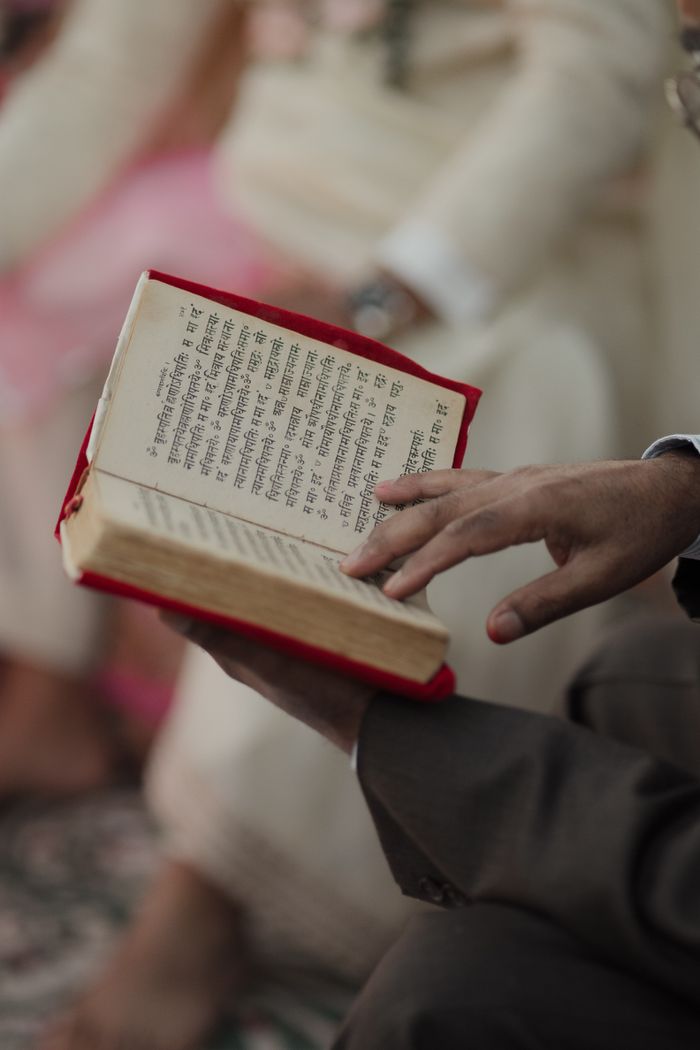 Close-up of a person reading a traditional religious book in a ceremonial setting.